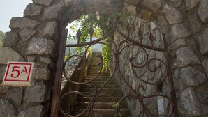Ein steinernes Bogenportal führt zu einer Treppe mit einem Metallgeländer.