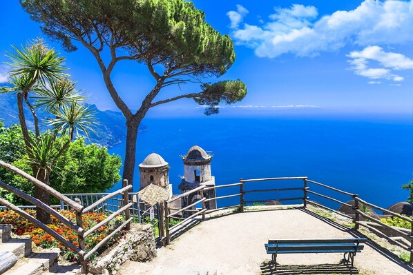 A coastal viewpoint with a wooden staircase leading to a bench overlooking the sea.