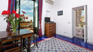 Ein Zimmer mit einem Esstisch, Stühlen, einem Holzkabinett, einem Fernseher und einem gemusterten Teppich.