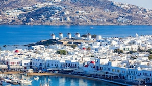 A coastal town with white buildings, a harbor with boats, and windmills on a hill. - Rose Studio Two with shared pool and sea view (Mykonos)