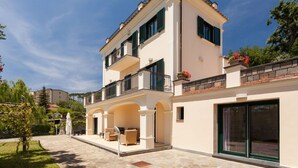 A two-story building with a balcony, a covered patio area with outdoor furniture, and a large sliding glass door. - Villa Castore with private pool - My Rental Homes (Massa Lubrense)