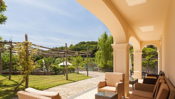 A covered outdoor seating area with wicker furniture and a pergola. - Villa Castore with private pool - My Rental Homes (Massa Lubrense)