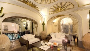 Una lujosa habitación de hotel con una cama grande, una mesa de comedor con desayuno servido y vista al baño.