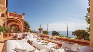 Una terraza con mobiliario blanco, vistas al mar y plantas en macetas.