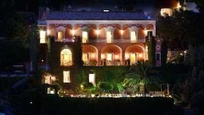 A multi-story building with balconies, arched windows, and a well-lit facade. - Villa Elyseum with swimming pool - My Rental homes (Positano)