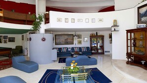 Amplia sala de estar con mesa de billar, sofás azules y una mesa de centro de vidrio.