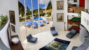 Una sala de estar moderna con un amplio ventanal, piscina y mesa de billar.