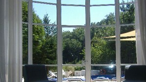 Una habitación amplia con ventanas grandes, una zona de estar con dos sillones y una mesa de vidrio.