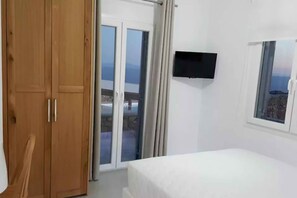 A bedroom with a bed, a TV mounted on the wall, and a window with a view of the sea. - My Rental Homes - Villa Pirgi with swimming pool and panoramic sea views. (Paraga)
