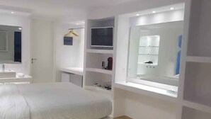 A modern hotel room with a large bed, a TV, a mirror, and a bathroom with a shower. - My Rental Homes - Villa Pirgi with swimming pool and panoramic sea views. (Paraga)