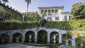 Un edificio histórico con un patio central, un puente de piedra y un jardín bien cuidado.