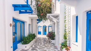 A narrow, stone-paved alleyway flanked by white buildings with blue doors and shutters. - My Rental Homes - Villa Rose 1, only 1 km from Agios Stefanos beach. Shared pool (Mykonos)