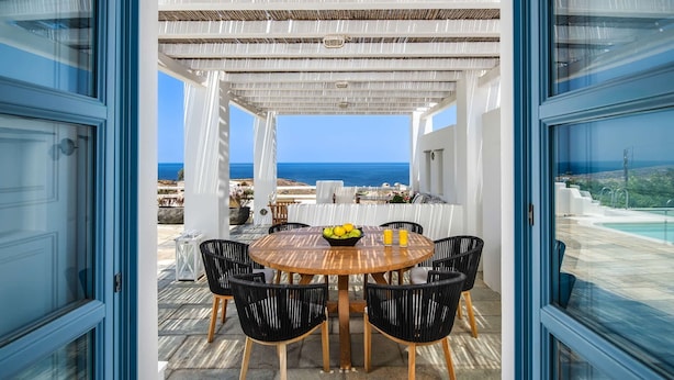 A covered outdoor dining area with a table and chairs, overlooking a pool and the sea. - My Rental Homes - Villa Tramountana with pool and large outdoor spaces with BBQ (Fira)