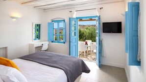 A bedroom with a bed, a desk, a chair, a TV, and a balcony with a table and chairs. - My Rental Homes - Villa Tramountana with pool and large outdoor spaces with BBQ (Fira)