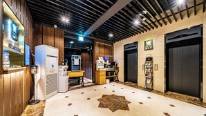 A hotel lobby with a reception desk, a minibar, a coffee machine, and two elevators. - SKYHOTEL (Yongin)