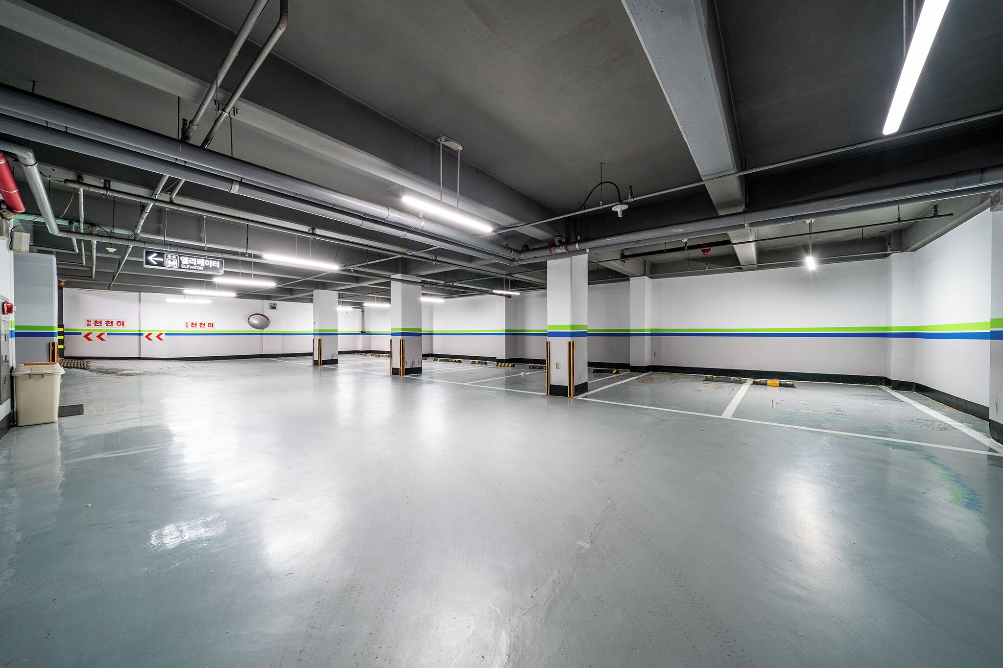 A spacious, well-lit parking garage with clear directional signage and a clean, polished floor.