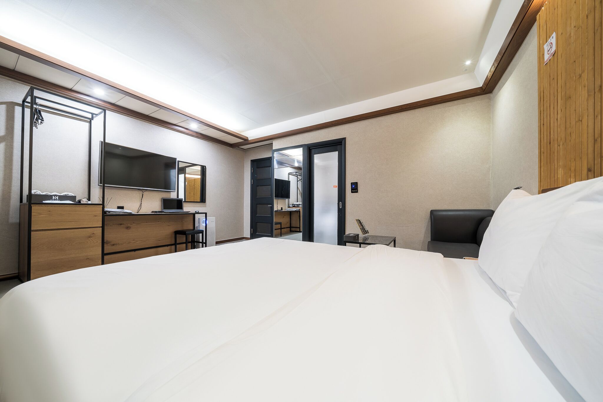Una habitación de hotel con una cama grande, un escritorio con computadora, televisor y espejo.