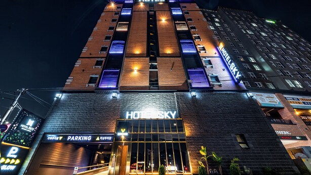 A hotel with a prominent 'HOTEL SKY' sign, a parking entrance, and a modern architectural design with illuminated windows. - SKYHOTEL (Yongin)