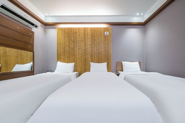 A hotel room with two single beds, a wooden headboard, a mirror, and an air conditioning unit. - SKYHOTEL (Yongin)