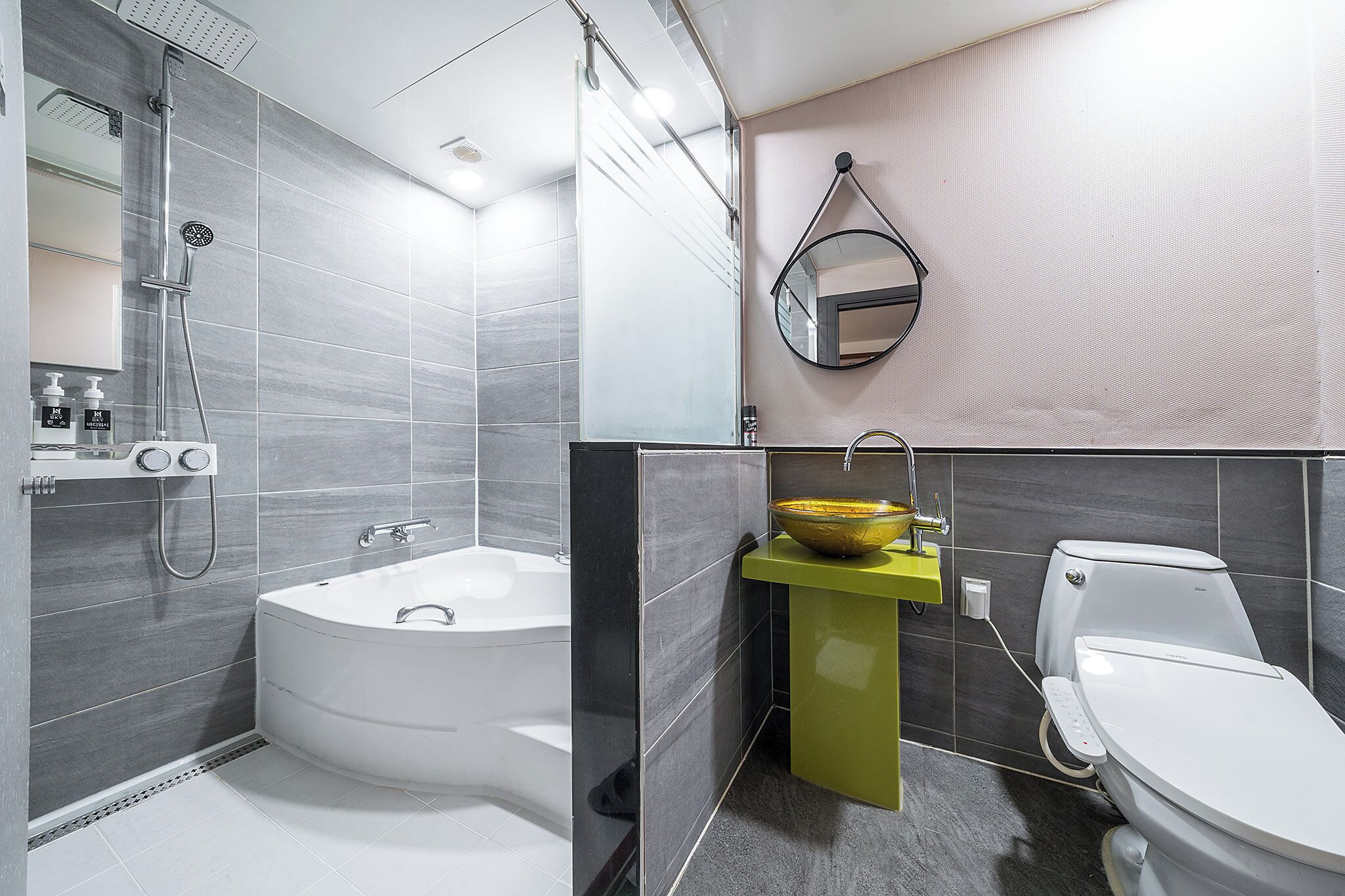 Un baño moderno con una bañera independiente, un lavamanos con pedestal amarillo y un inodoro.