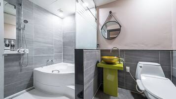 Un baño moderno con una bañera independiente, un lavamanos con pedestal amarillo y un inodoro.
