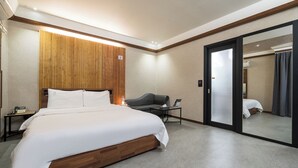 A modern hotel room with a large bed, a desk, a chair, and a mirror. - SKYHOTEL (Yongin)