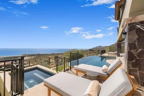 A rooftop infinity pool with lounge chairs, a stone wall, and a view of the ocean. - 4BD Oceanfront Montecristo Estates Villa (Cabo San Lucas)