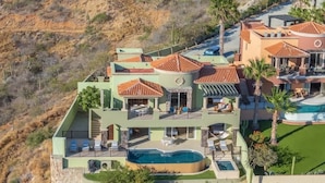 Une maison à plusieurs étages dotée d’une piscine, d’un espace salon extérieur et offrant une vue sur le paysage environnant.