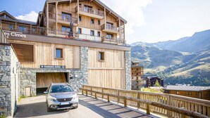 Un bâtiment en bois doté de balcons, avec une voiture garée devant.