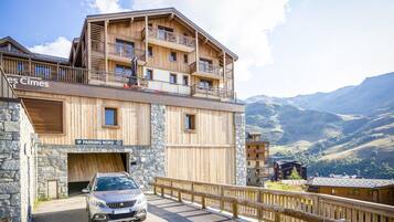 A wooden building with balconies and a car parked in front.