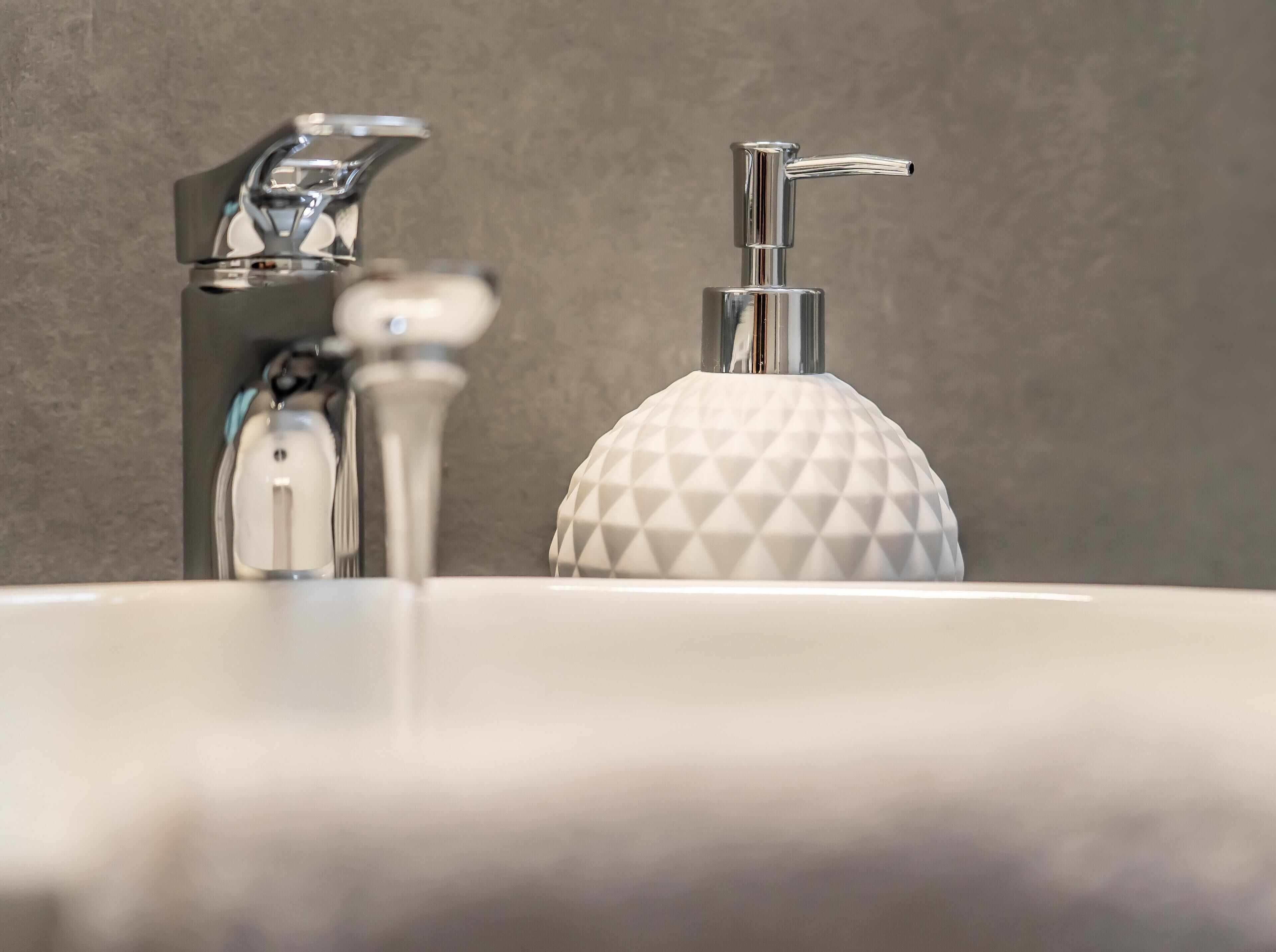 Un lavabo de salle de bain doté d’un robinet moderne et d’un distributeur de savon aux formes géométriques.