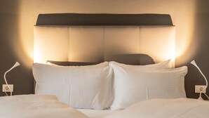 Una cama bien hecha con sábanas blancas y un cabecero con iluminación integrada.
