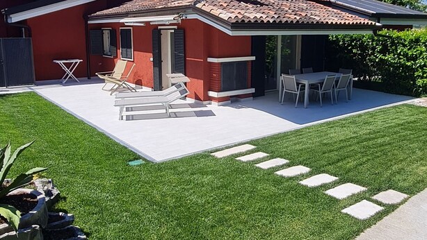 Una casa roja con patio, césped y un muro de piedra.