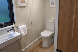 A small, clean bathroom with a white sink, a towel hanging on a rack, a toilet, and a window with a view. - Not Available for Rent (Whitchurch)