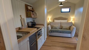 A compact kitchen with a sink, toaster, and oven, and a cozy living area with a sofa and pillows. - Not Available for Rent (Whitchurch)