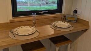 A dining area with two sets of plates, cutlery, and glasses on a wooden counter. - Not Available for Rent (Whitchurch)