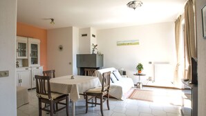A dining area with a table and chairs, a bed, a small table with a plant, and a radiator. - Jonah House (Maccagno con Pino e Veddasca)