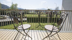 A balcony with two metal chairs and a small table, overlooking a neatly trimmed garden and distant mountains. - Jonah House (Maccagno con Pino e Veddasca)