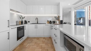 A modern kitchen with white cabinetry, a black faucet, and a herringbone-patterned backsplash. - Corporate Abode South Yarra by Ready Set Stay (South Yarra)