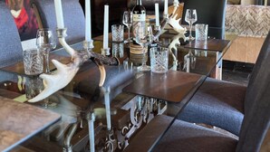 Ein Essbereich mit einem Holztisch, gedeckt für sechs Personen, mit Hirschgeweih-Dekorationen, Weingläsern und Kerzen.