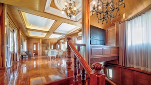 A spacious interior with a wooden staircase, high ceilings, and large windows. - 4 BR Royal Boat Pool Villa – Pattaya's Hidden Haven (Muang Pattaya)