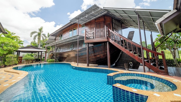 A swimming pool with a wooden deck and a covered area. - 4 BR Royal Boat Pool Villa – Pattaya's Hidden Haven (Muang Pattaya)