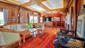 A spacious living area with wooden flooring, a sofa set, a coffee table, and a television. - 4 BR Royal Boat Pool Villa – Pattaya's Hidden Haven (Muang Pattaya)