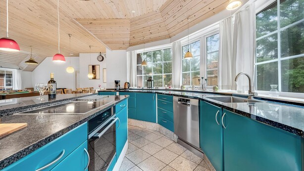 Une cuisine moderne avec des armoires de couleur turquoise, des comptoirs en granit et un plafond en bois.