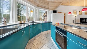 Une cuisine moderne avec des armoires de couleur turquoise, des comptoirs en granit et des luminaires suspendus.