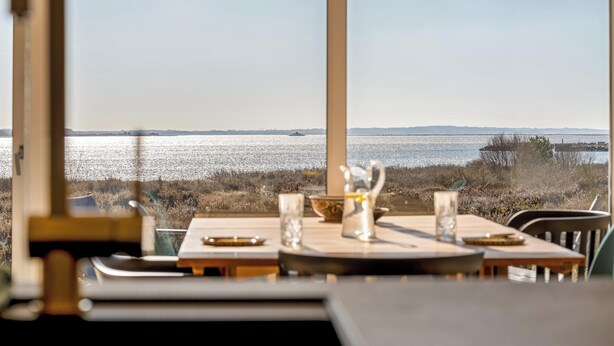 Une table à manger offrant une vue sur l’eau et sur la terre, au loin.