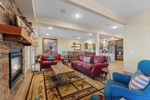 A spacious living room with a fireplace, red leather sofas, a coffee table, and a blue armchair.
