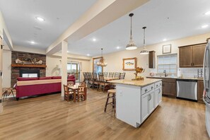 A spacious kitchen with a central island, wooden dining table, and chairs, a red sofa, and a fireplace. - Gorgeous Hilltop Lake View!  Great Location! (Branson)
