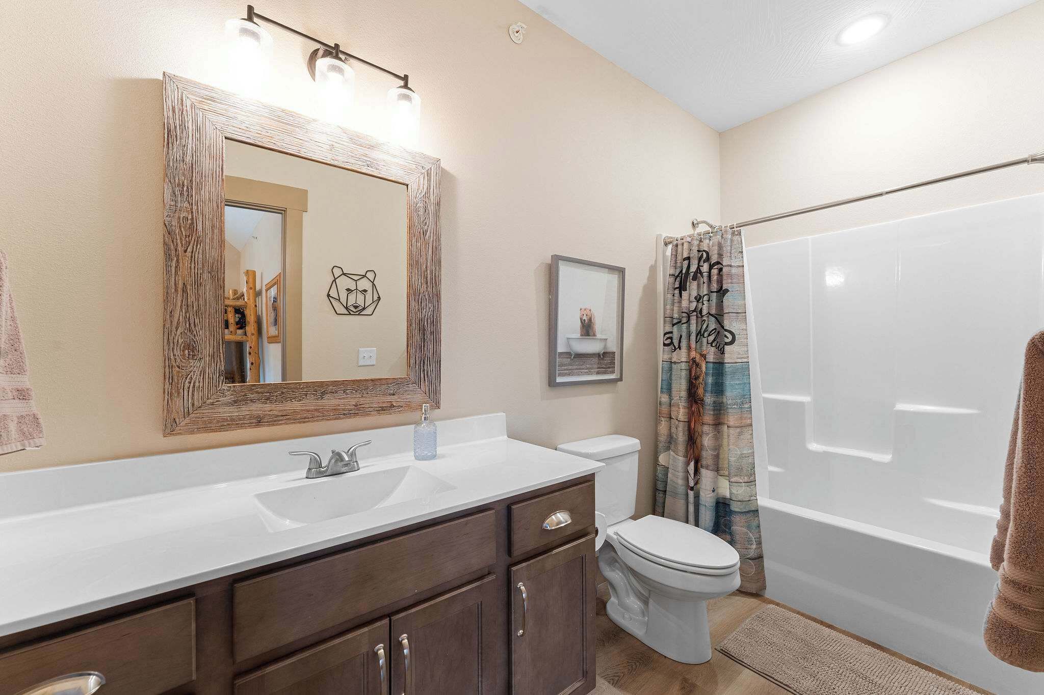 A bathroom with a white sink, dark wooden vanity, a white toilet, and a bathtub with a shower curtain.
