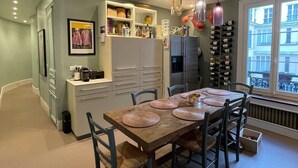 A modern kitchen with a dining area, featuring a wooden table, chairs, and pendant lights.